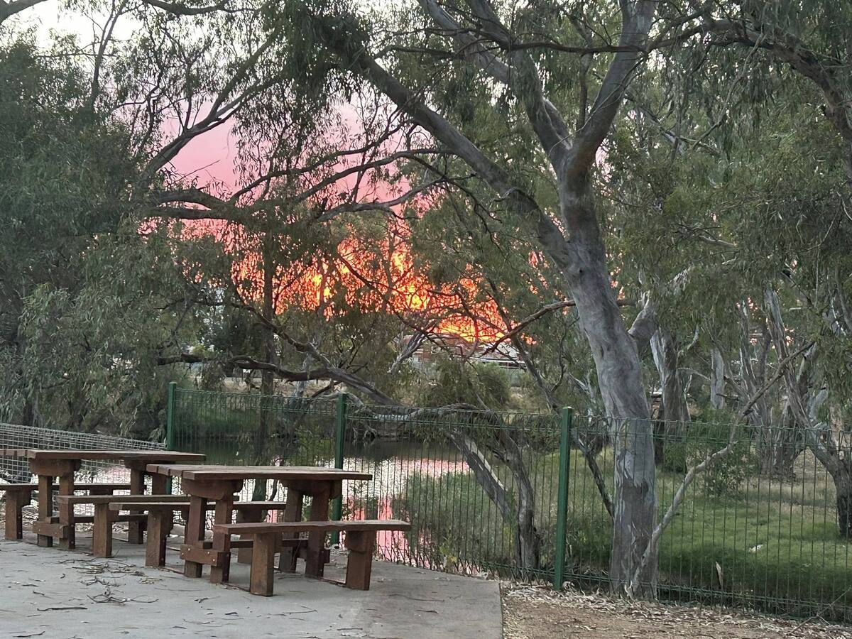 Picnic tables and fire-orange sunset by the river